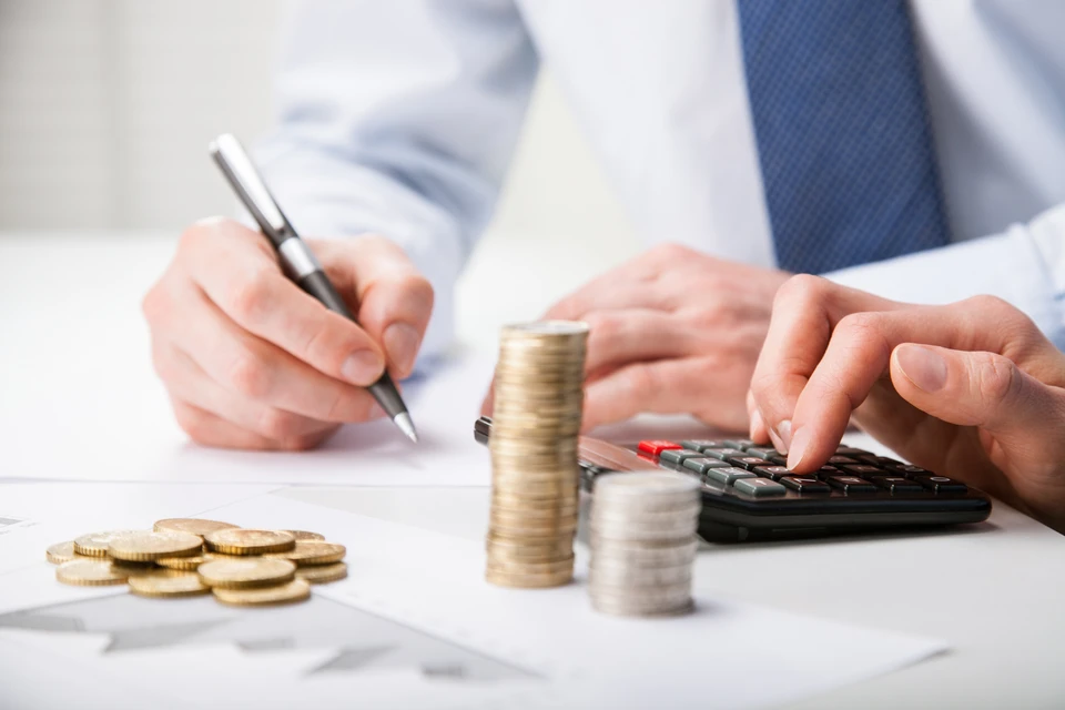 Scène d'intérieur professionnel montrant une personne en costume-cravate effectuant des calculs financiers