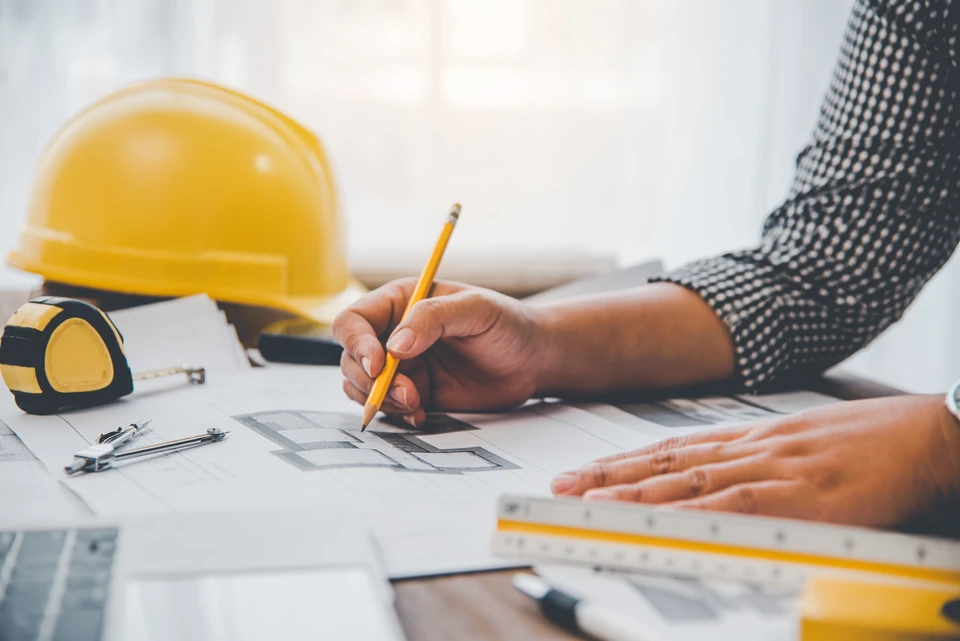 Équipe d'ingénieurs et d'architectes civils professionnels tenant un document de plan de projet, supervisant et contrôlant les travaux de construction sur le chantier de construction