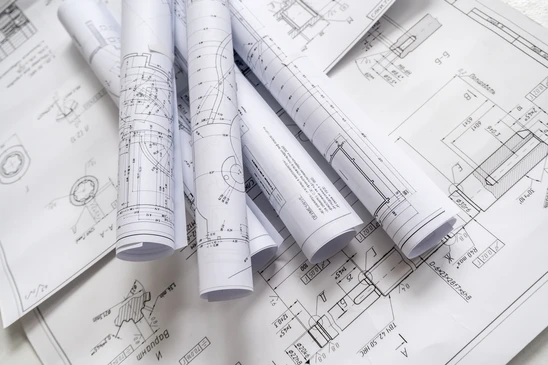 Plans d'architecture &eacute;tal&eacute;s sur surface de travail avec maquette miniature en bois repr&eacute;sentant une maison